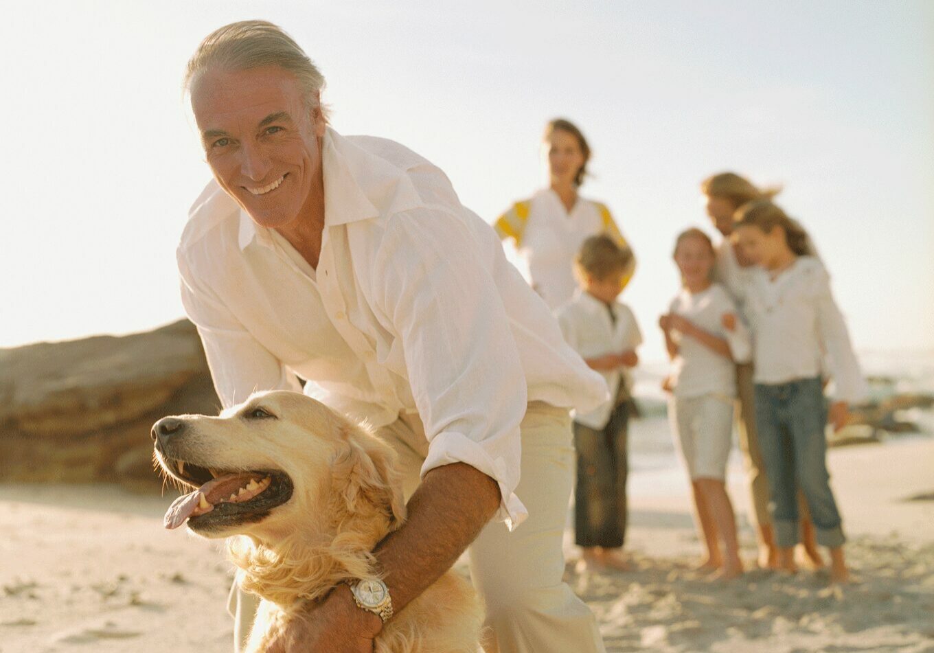 A man and his dog on the beach with people