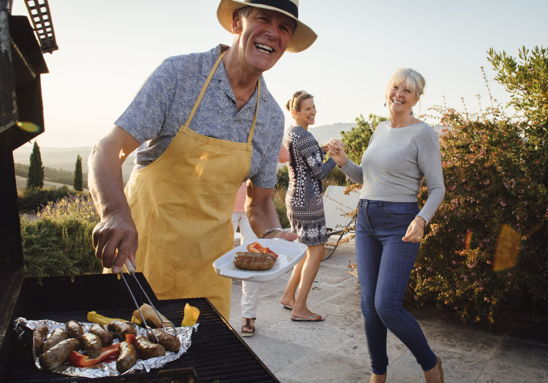A man and two women grilling food on an outdoor grill.